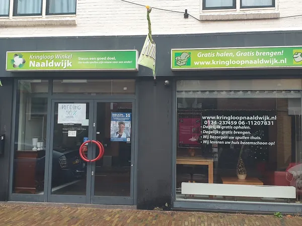Winkelgevel met groene borden en zwarte puien, twee etalageruiten, deur met rood ringen opknoping en straatview