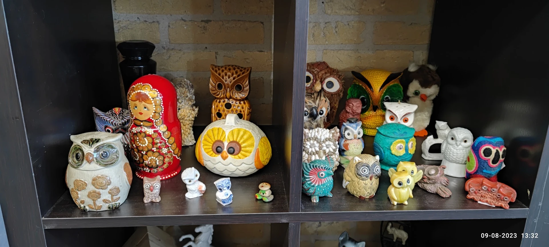 Verzameling decoratieve uilen en poupées in verschillende stijlen en kleuren in een glazen vitrine