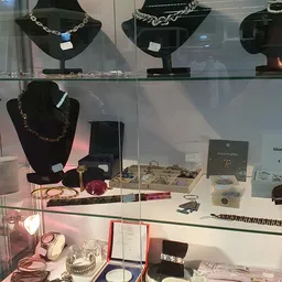 Glazen vitrine met sieraden, kettingen, ringen en accessoires uitgestald op wit oppervlak