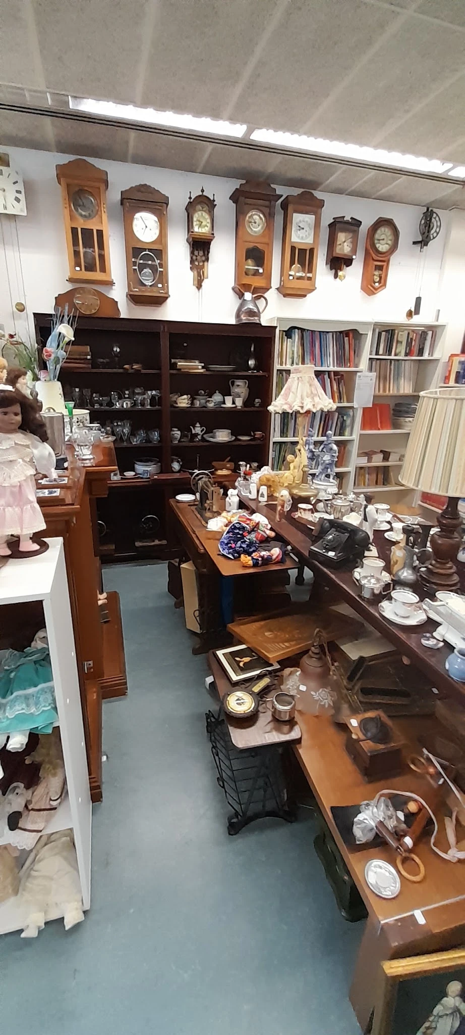 Winkelbinnenruimte met houten meubelen, boeken in kasten, serviesgoed en decoratieve voorwerpen