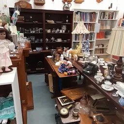 Winkelbinnenruimte met houten meubelen, boeken in kasten, serviesgoed en decoratieve voorwerpen