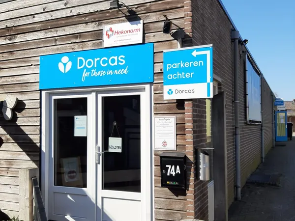 Voorgevel van kringloopwinkel met blauwe Dorcas-bord en parkeerachter-waarschuwingsbord