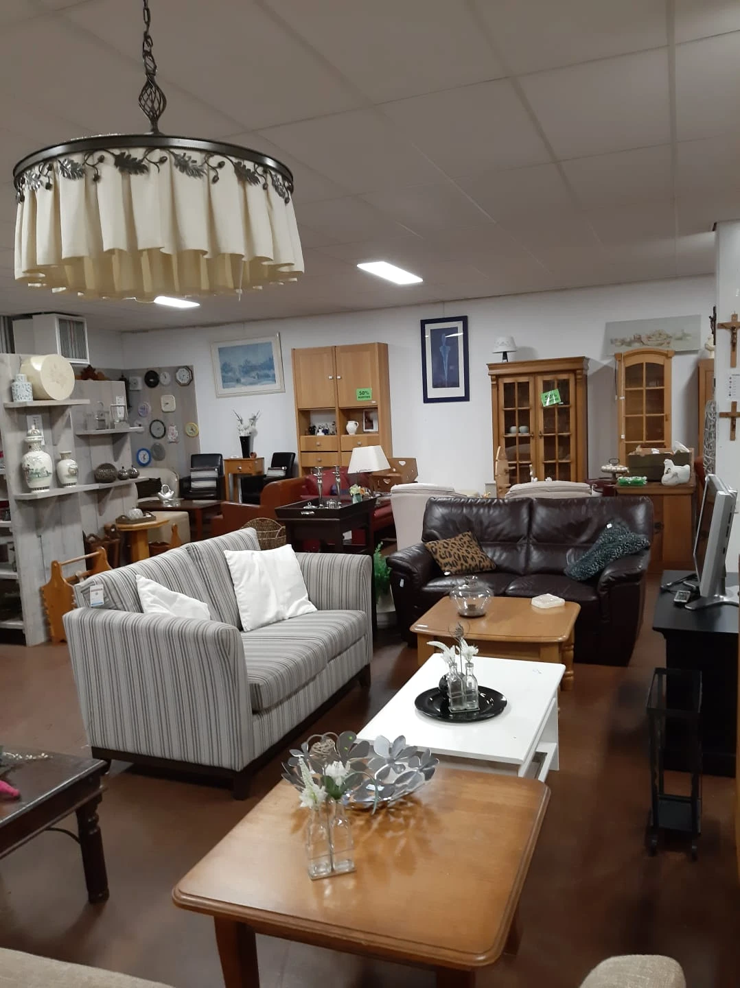 Woonkamer-opstelling met gestreepte fauteuil, zwarte leren bank, houten kasten en diverse meubels en decoratie-items