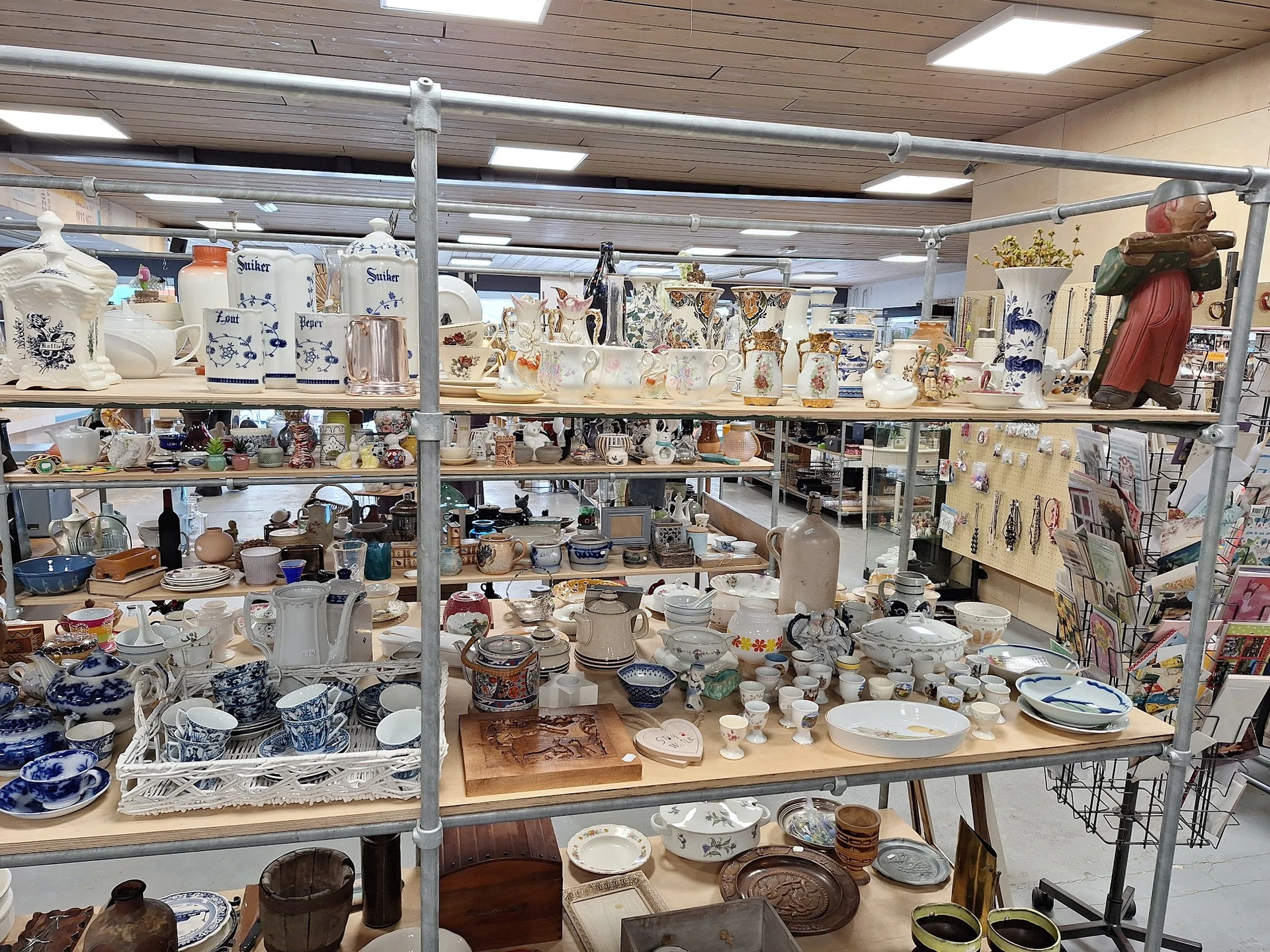 Uitgestalde serviesgoed, vazen, decoratieve items en huishoudelijke artikelen op planken en tafels in de winkel