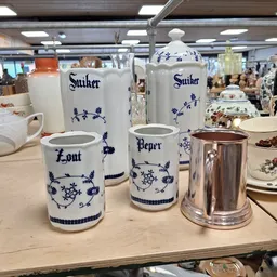 Blauw-wit porselein serviesgoed met scheepsdecoratieve motieven, waaronder zoutvaatjes, peperbussen en andere tafelstukken