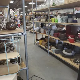 Metalen stellingen met huishoudelijke artikelen: pannen, potten, bakjes en ander kookgerei in verschillende kleuren