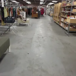 Winkelvloer van een kringloopwinkel met stellingen, kledingrekken en boekenkasten langs de zijkanten