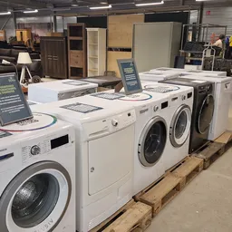 Uitgestalde wasmachines en droogkasten in wit en zwart op houten pallets in de winkel
