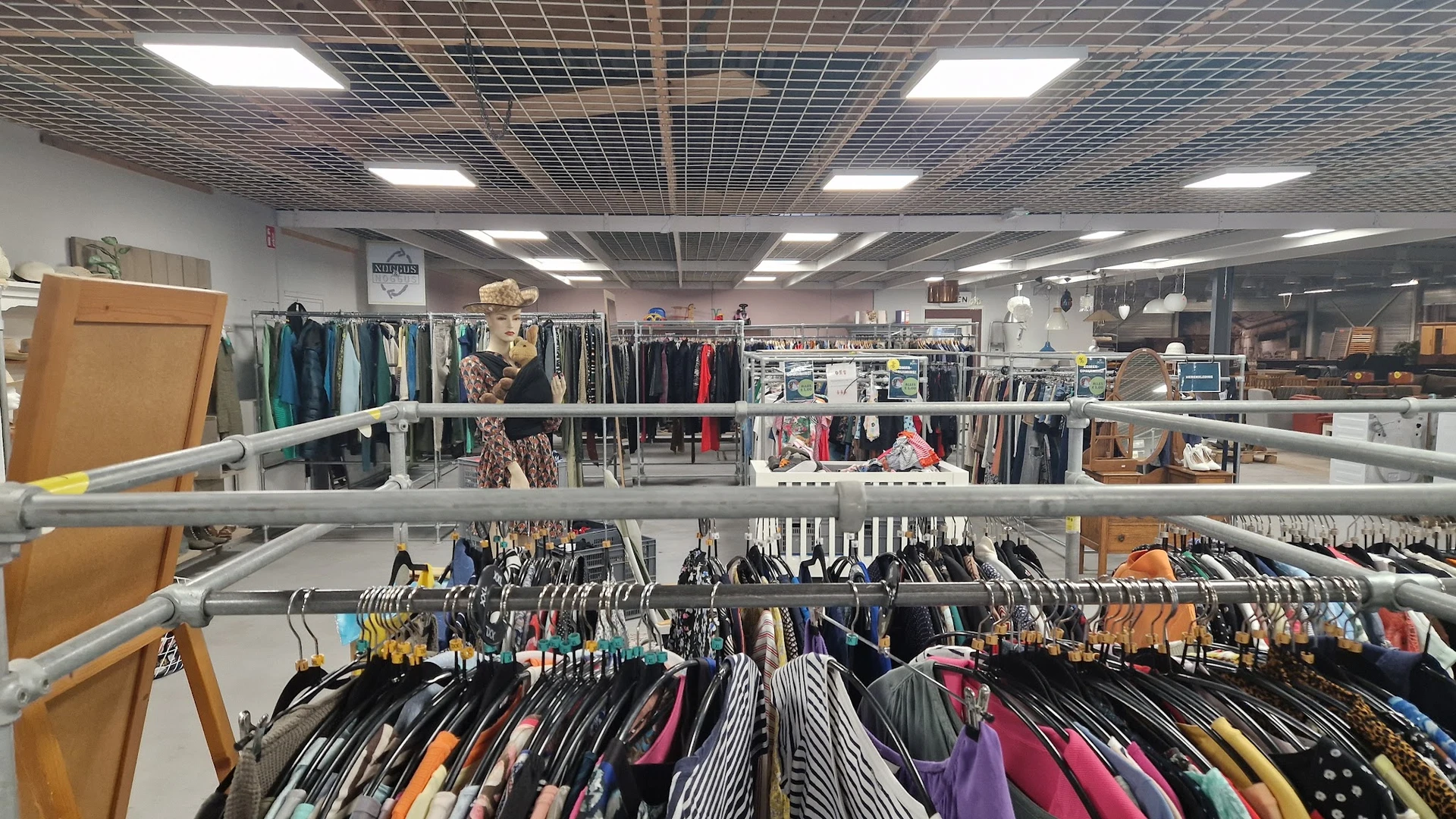 Rekken met tweedehands kleding op hangers, georganiseerd op meerdere verdiepingen in de winkel