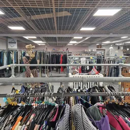 Rekken met tweedehands kleding op hangers, georganiseerd op meerdere verdiepingen in de winkel