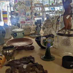Tafel vol diverse tweedehands huishoudartikelen: servies, beeldjes, decoratieve objecten en aardewerk