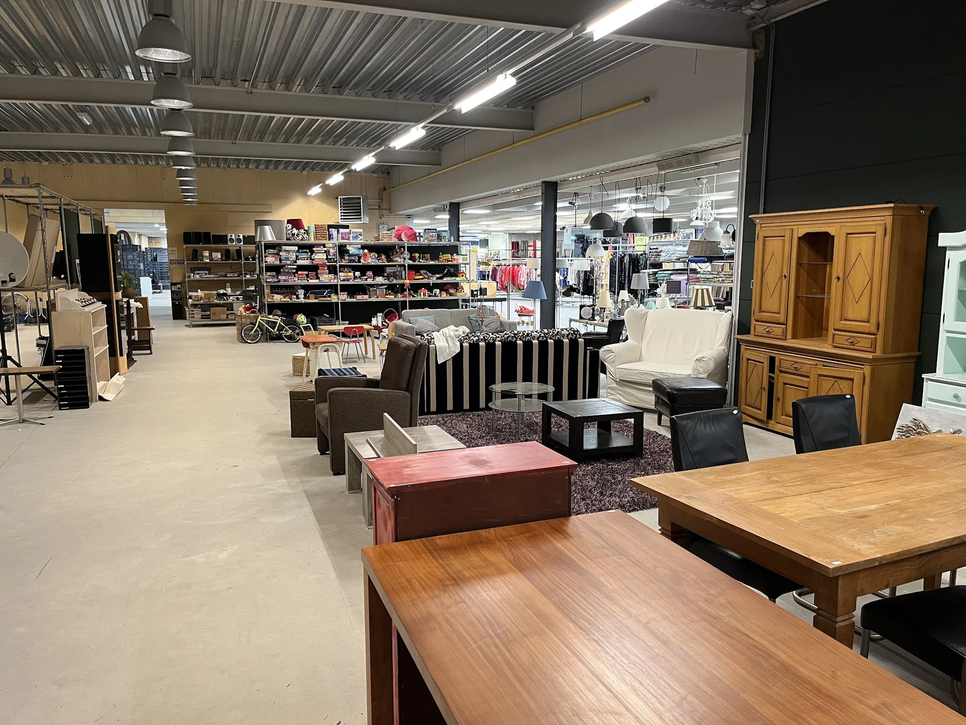 Ruim winkels interieur met meubels, kledingrekken en huishoudartikelen uitgestald