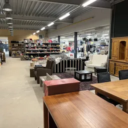 Ruim winkels interieur met meubels, kledingrekken en huishoudartikelen uitgestald