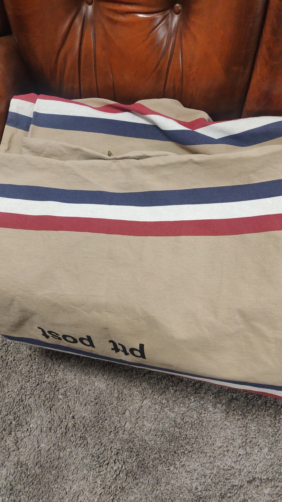 Close-up van beige kledingstuk met blauwe, witte en rode strepen