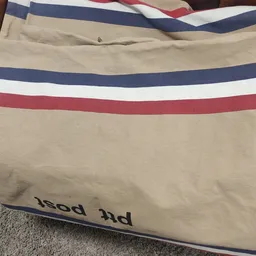 Close-up van beige kledingstuk met blauwe, witte en rode strepen