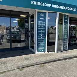 Winkelgevel met glazen deuren en ramen, informatieborden op de pui, straatafzetting zichtbaar