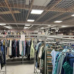 Rekken met tweedehands kleding in verschillende kleuren en stijlen in de winkel