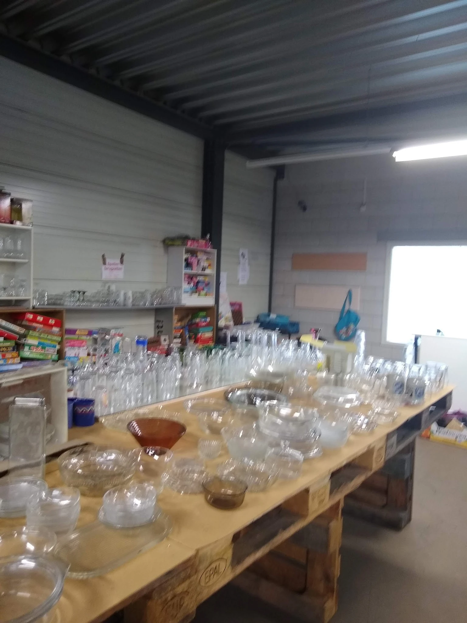 Tafel vol glazen bekers en potten, mogelijk voor verkoop in kringloopwinkel