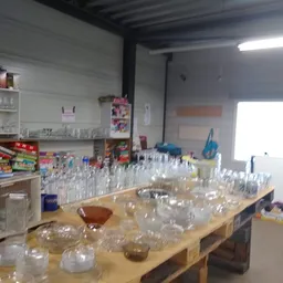 Tafel vol glazen bekers en potten, mogelijk voor verkoop in kringloopwinkel
