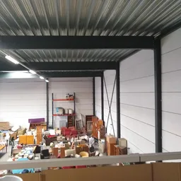 Opgeslagen meubels en spullen in een magazijn- of opslagruimte met metalen dakstructuur