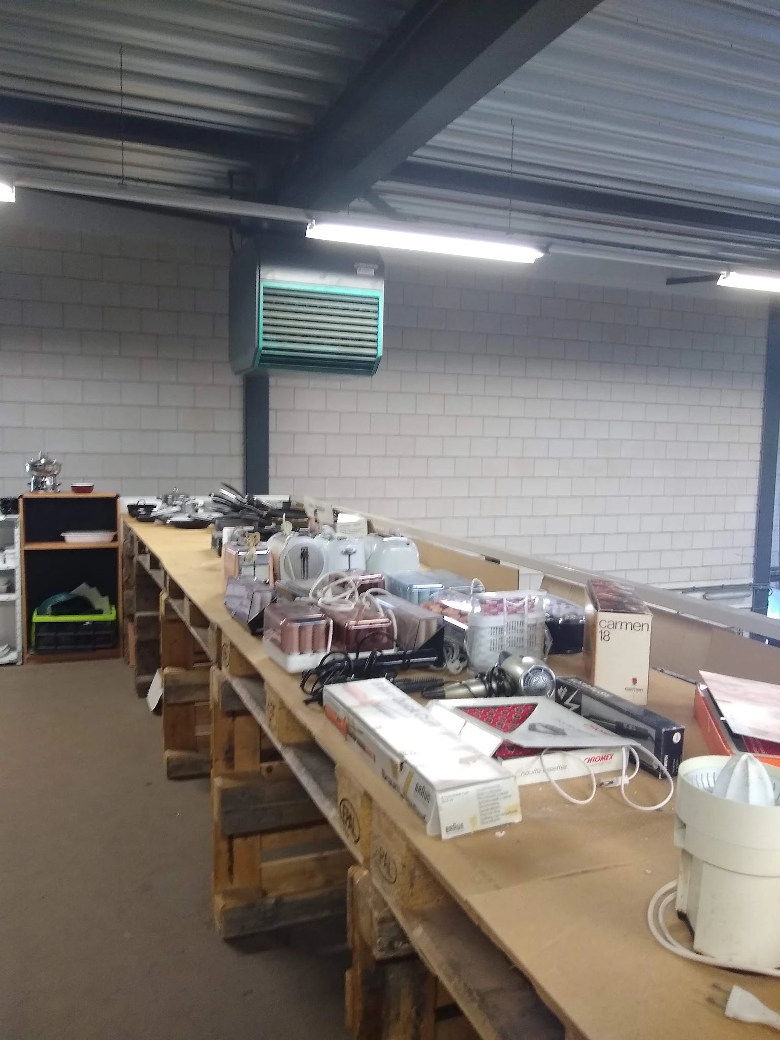 Lange tafel vol met diverse huishoudartikelen, electronica en spullen in kringloopwinkel
