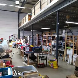 Overzicht van de winkelruimte met stellingen, boekenrekken, diverse spullen en gebruikte goederen verspreid door de hal