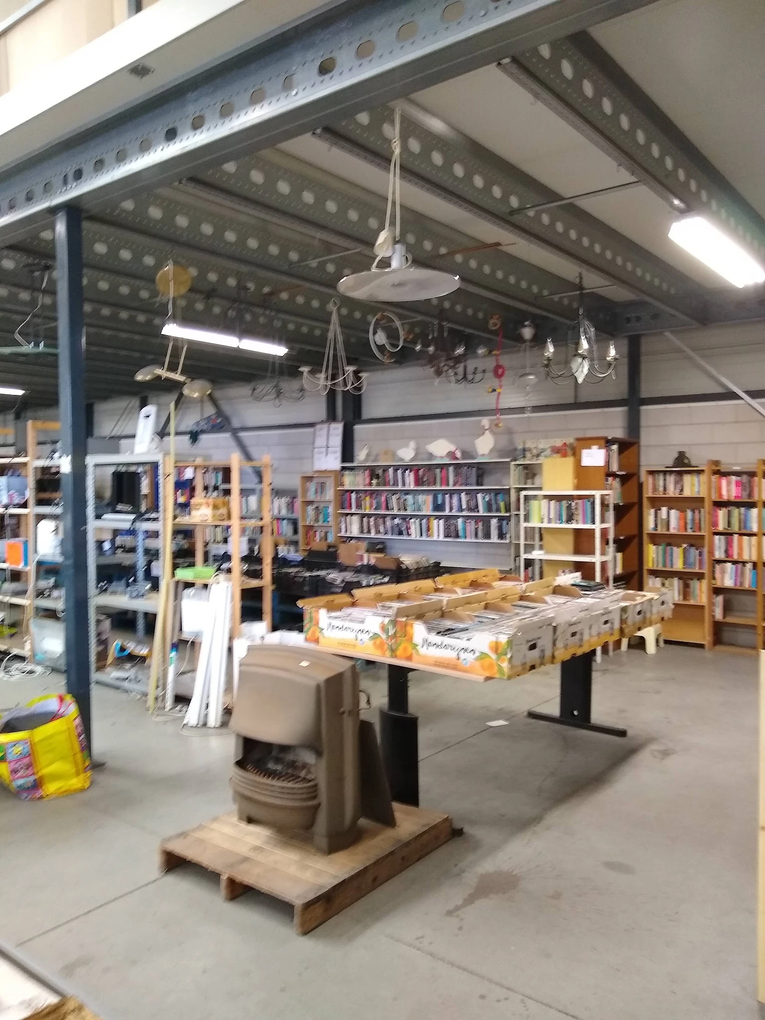 Ruim magazijn met boekenkasten, werkbank met materialen, bovenliggende LED-verlichting en diverse voorraad