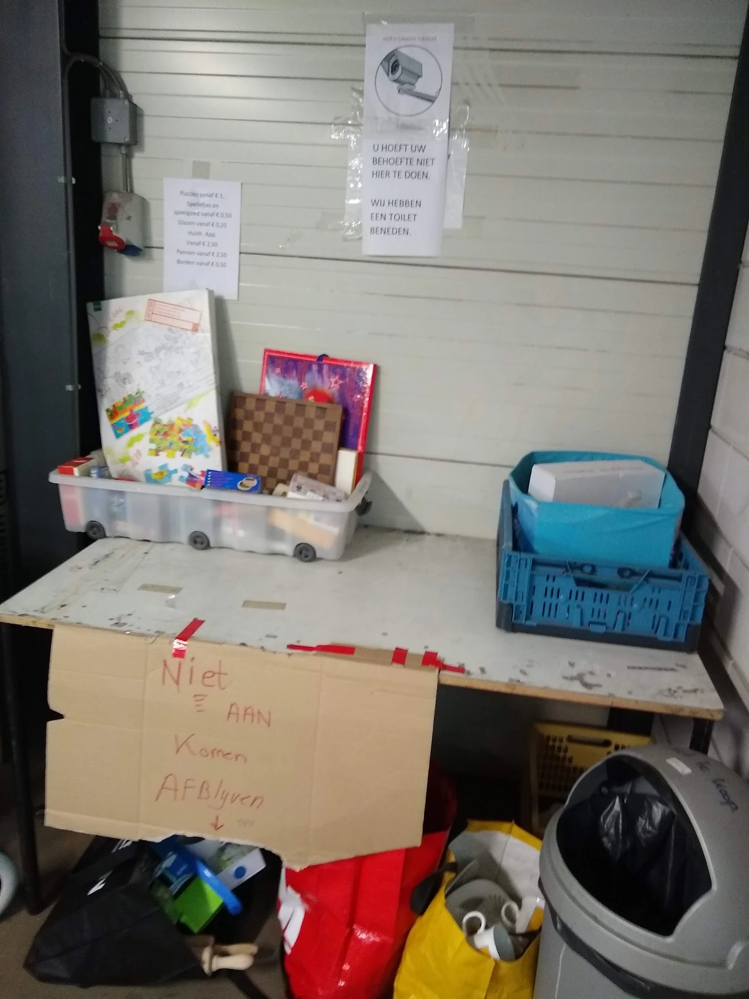 Werkplek met opbergboxen, dozen en spullen op een tafel tegen witte wand