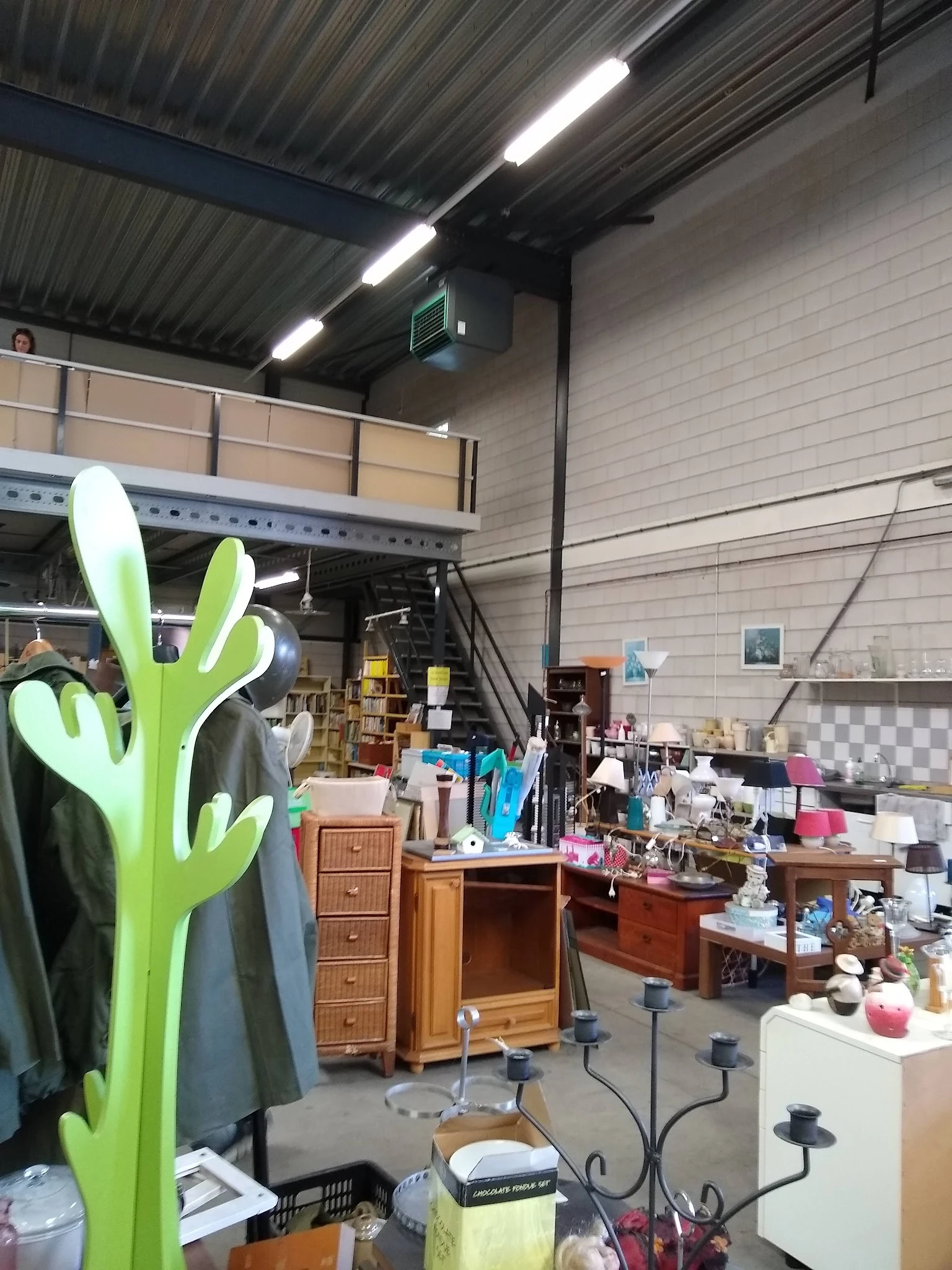 Overzicht van kringloopwinkel met diverse meubels, huishoudartikelen en decoratie waaronder een groen decoratief cactusbeeld