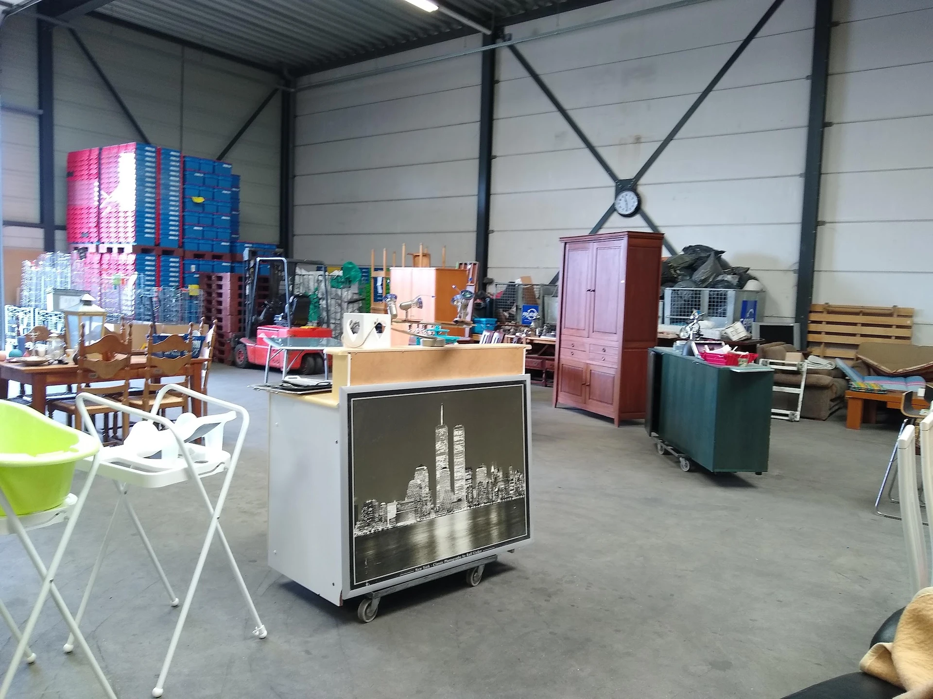 Magazijnruimte met diverse tweedehands meubels, stoelen, kasten en huishoudelijke spullen verspreid over de vloer