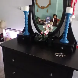 Zwarte kaptafel met blauwe kandelaars, spiegel en decoratie met kunstbloemen