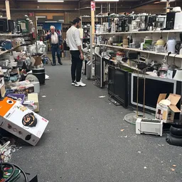 Winkelvloer van kringloopwinkel met stellingen vol huishoudartikelen, apparaten en diverse spullen
