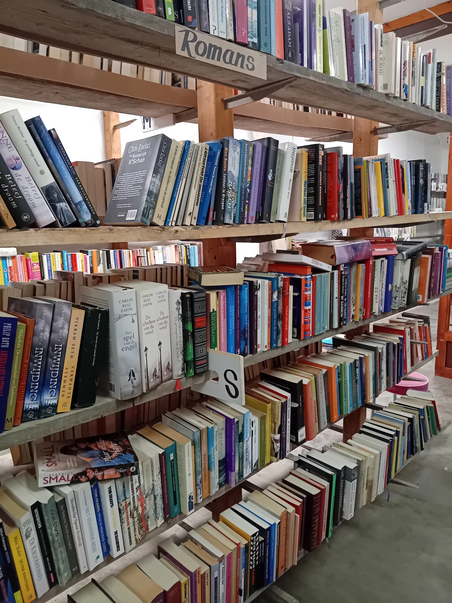 Boekenkasten en stellingen vol met tweedehands boeken in verschillende genres en kleuren