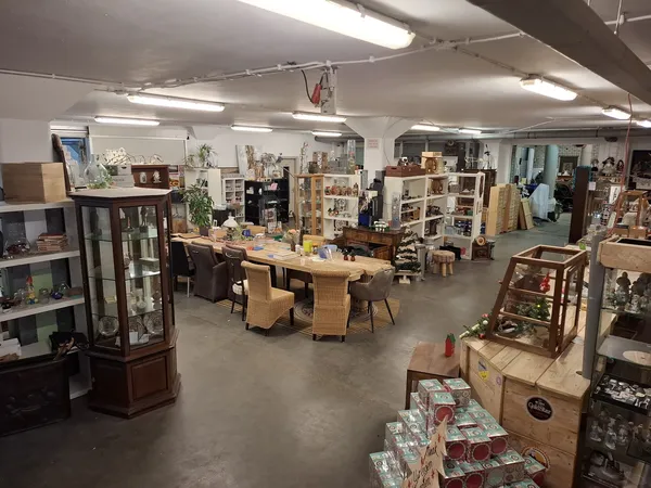 Overzicht van de winkelvloer met tafels, stellingen, vitrines en diverse tweedehands spullen