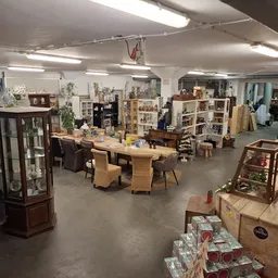 Overzicht van de winkelvloer met tafels, stellingen, vitrines en diverse tweedehands spullen