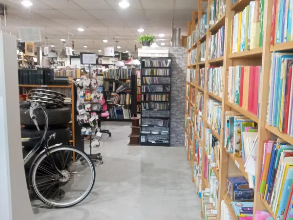 Boekenrekken met gekleurde boeken en een fiets in een kringloopwinkelinterieur