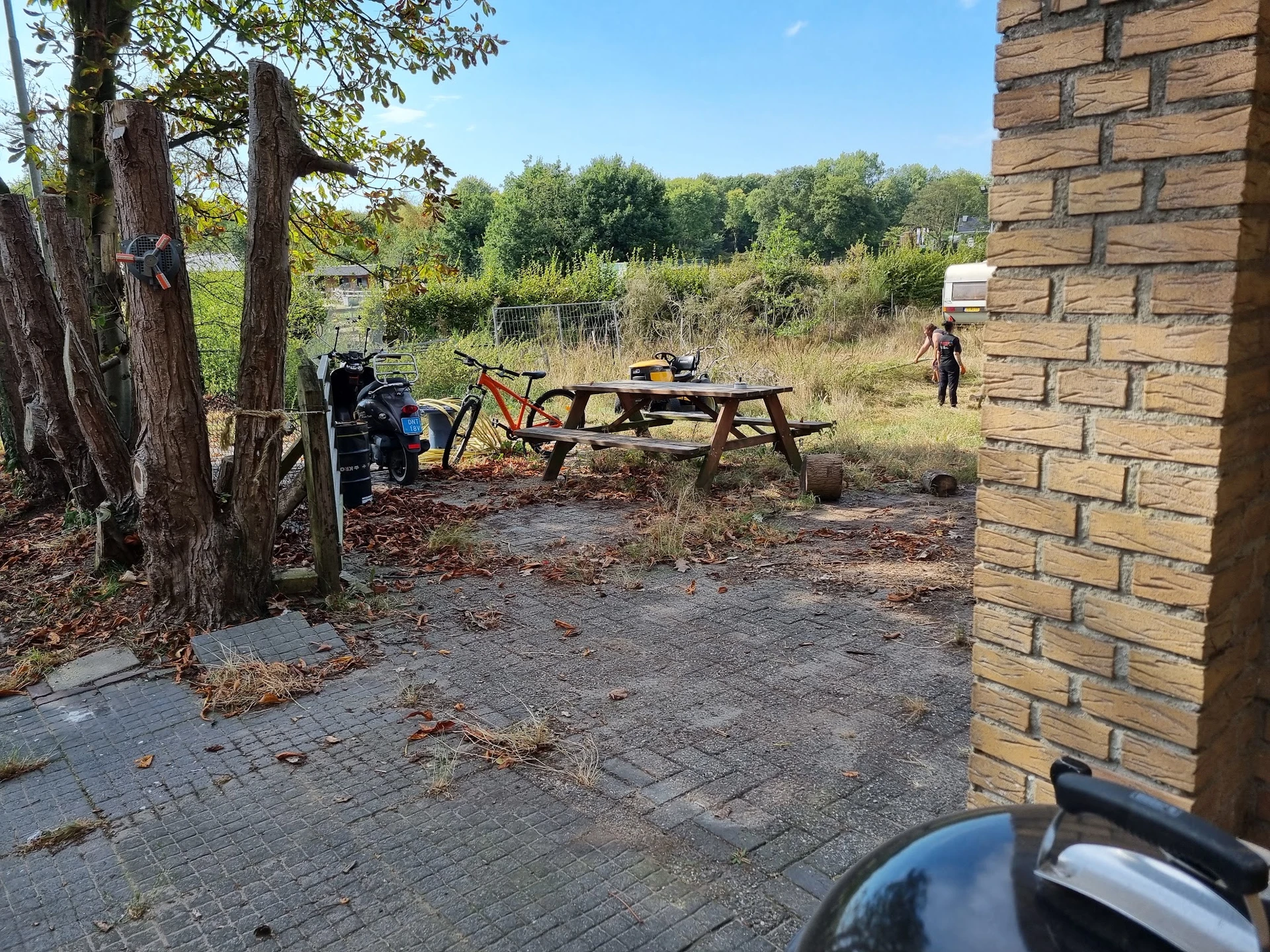 Picknickplaats met tafel, fiets en bakstenen gebouw aan de rand van een terrein