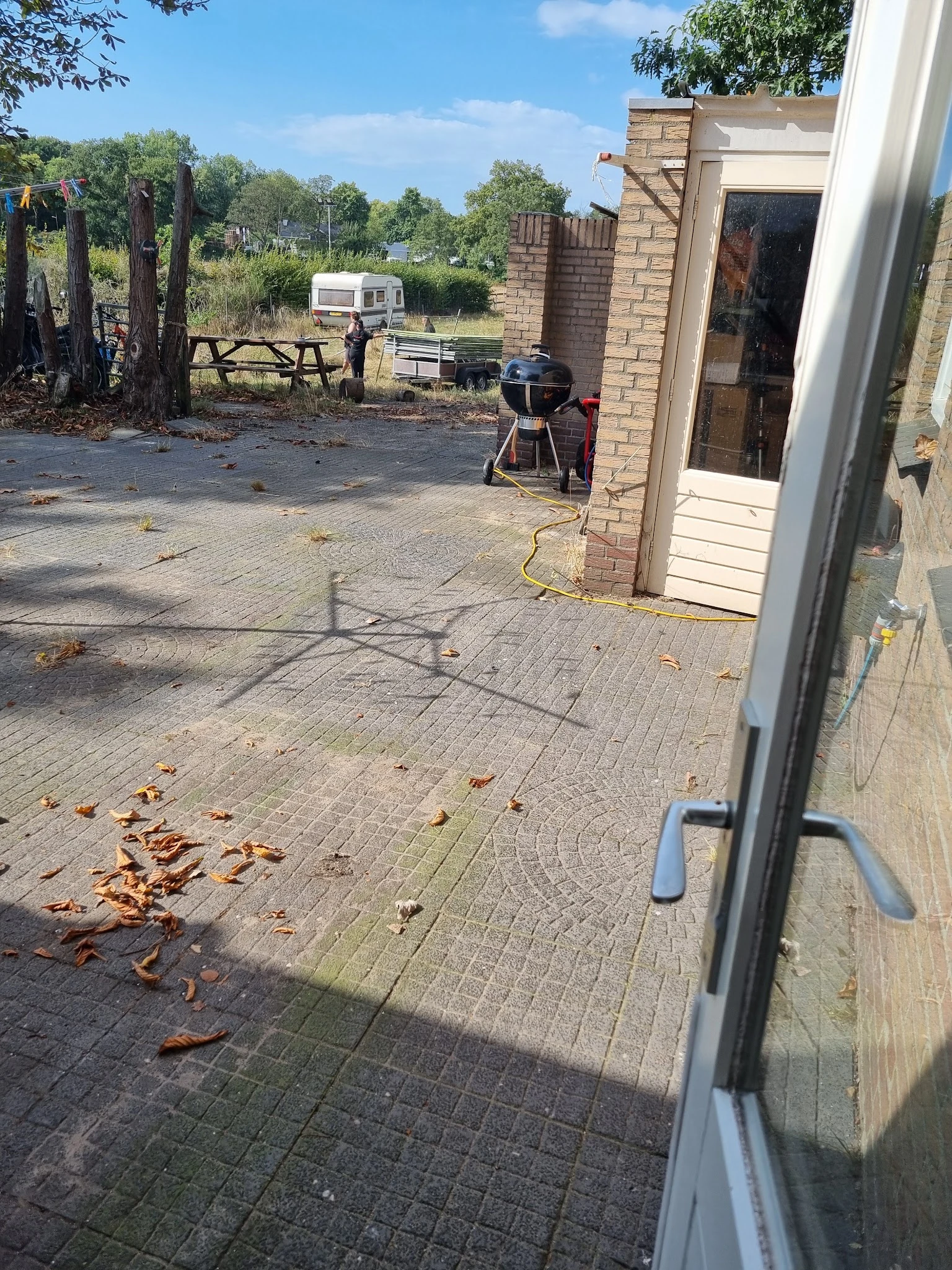 Voorkant van kringloopwinkel met bakstenen gevel, deur en terras met tuinstoelen