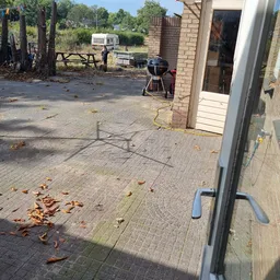 Voorkant van kringloopwinkel met bakstenen gevel, deur en terras met tuinstoelen