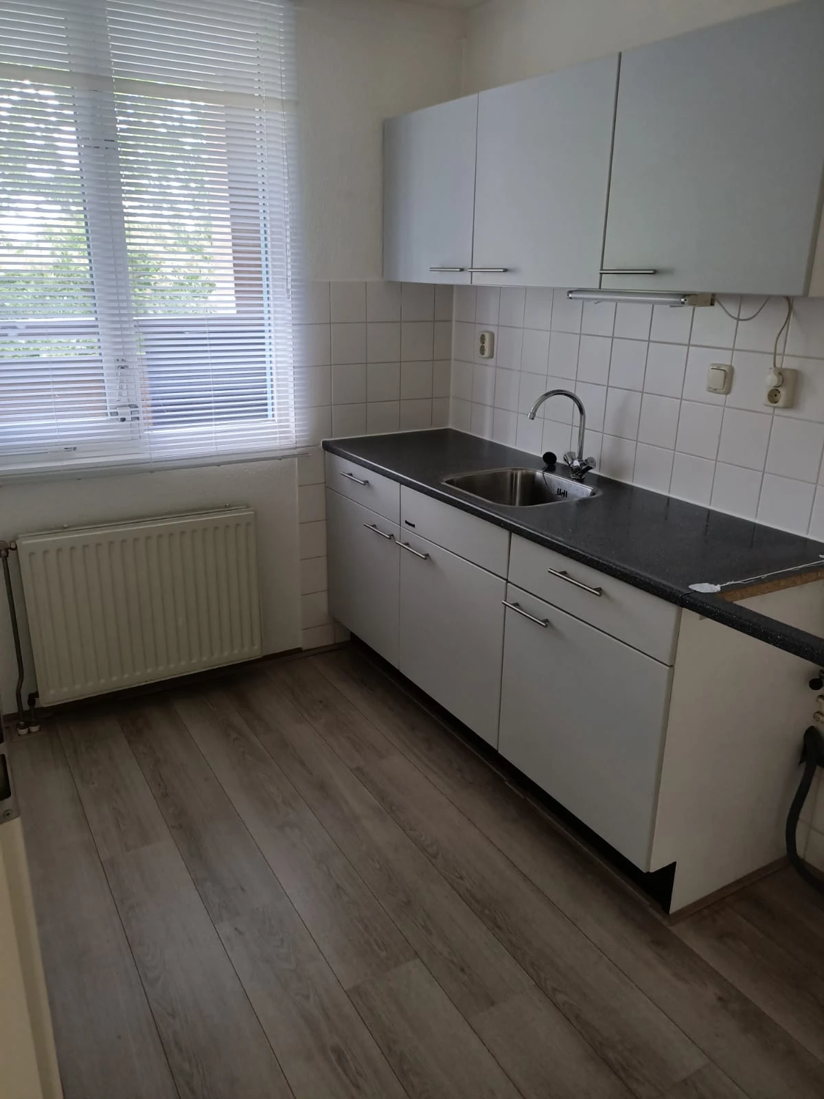 Witte keukenkasten met zwart blad en ingebouwde gootsteen in een keukenhoek