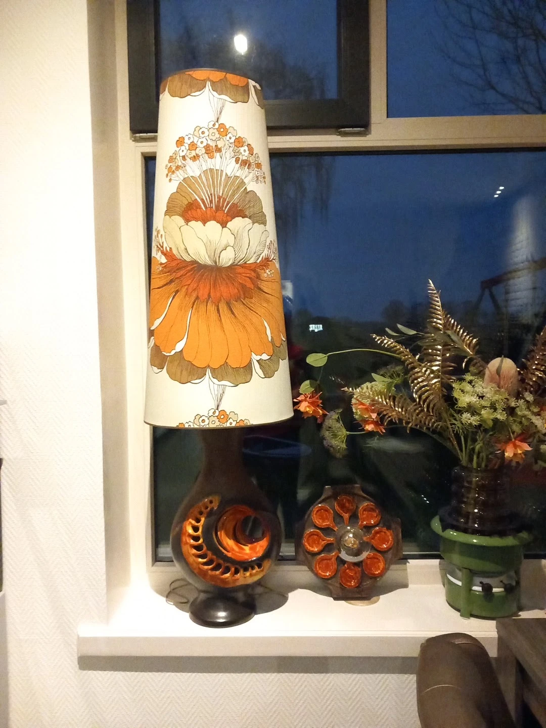 Decoratieve vaas met oranje bloemmotief en bloemenboeket in glazen vaas op winkelplank