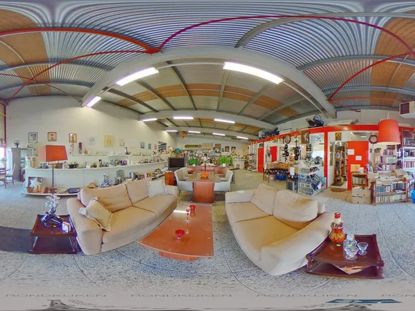 Winkelvloer van kringloopwinkel met beige zitmeubels, oranje tafels en rode kastjes met diverse spullen