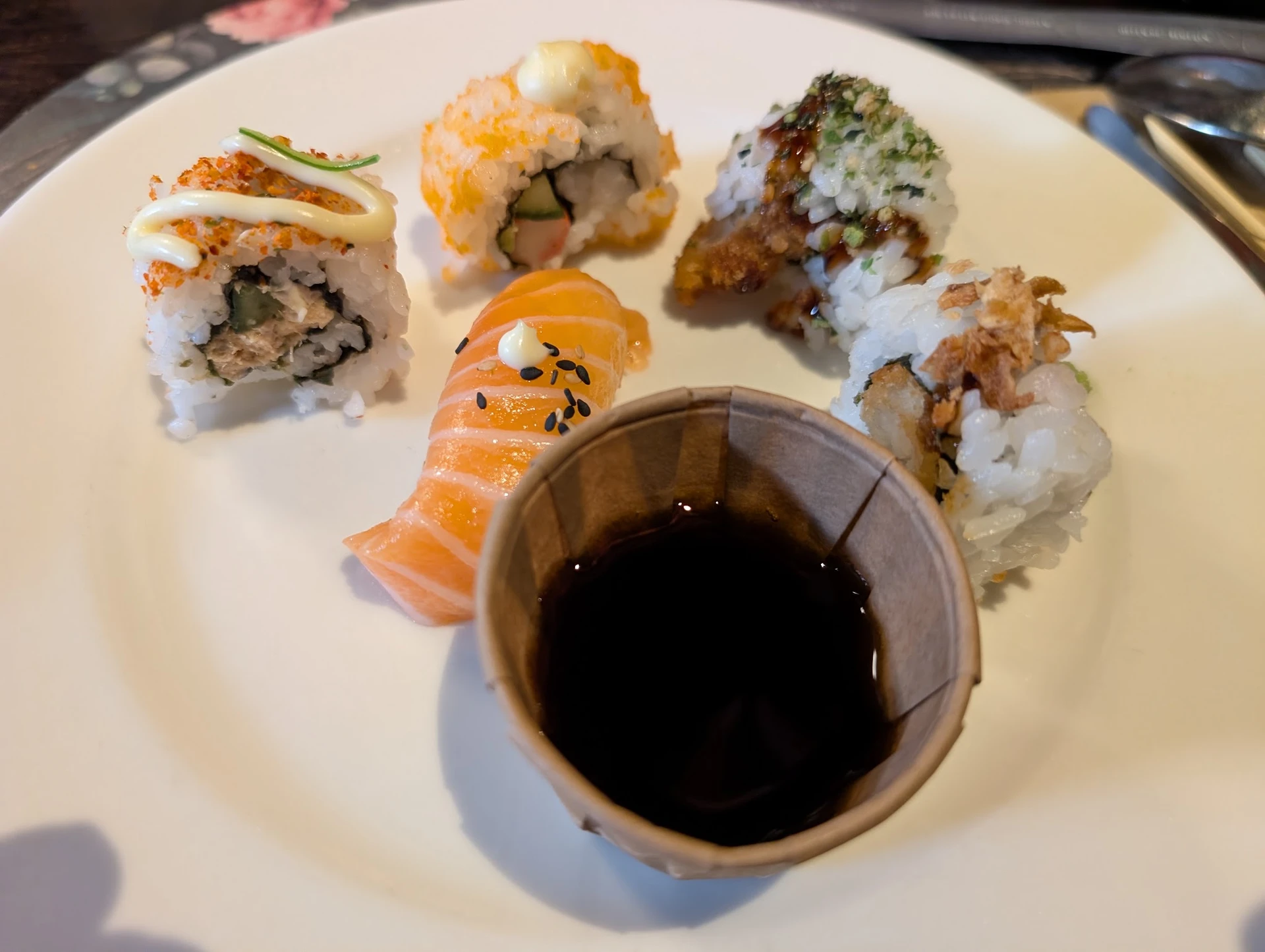 Bord met vier verschillende sushi rollen en een kommetje sojasaus