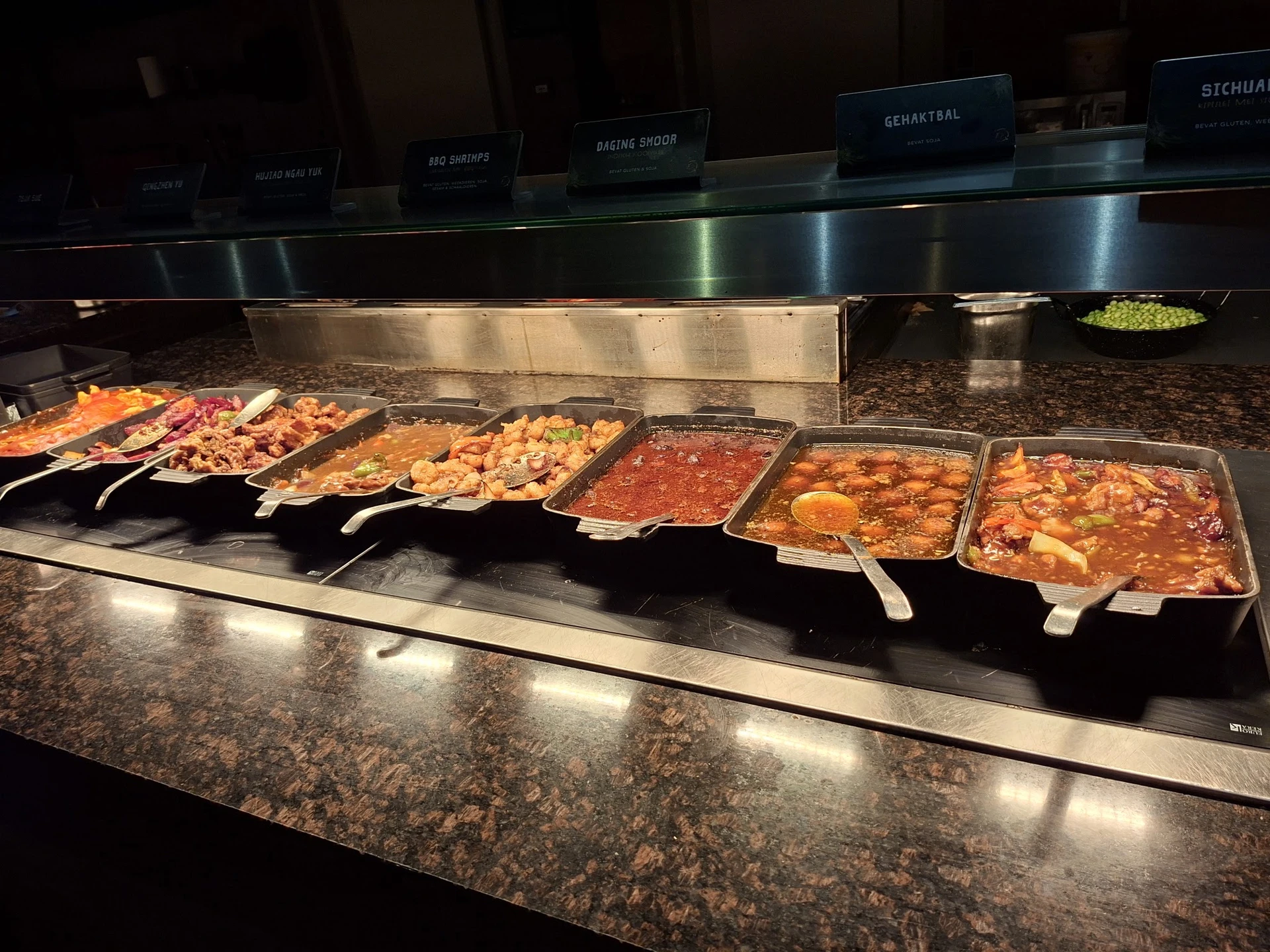 Warmhoudplateau met verschillende warme gerechten in bakken bij een lunchroom of eethoek