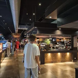 Winkelvloer met bezoekers bij een moderne lunchroom- of cafébalie met donkere afwerking en gouden accenten