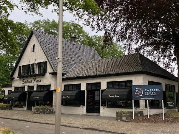 Witte kringloopwinkel met zwart dak en zwarte ramen, bord met 'Eastern Plaza' zichtbaar