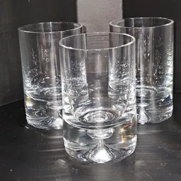 Vier lege glazen op donker oppervlak, mogelijk gebruikt servies