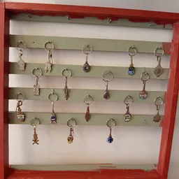 Verzameling sleutelhangers aan haken opgehangen op een groen-witte wand