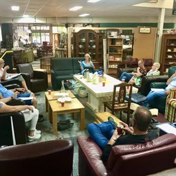 Groep bezoekers zit op verschillende stoelen en banken in een gezellige zithoek met tafels, drinken en hapjes
