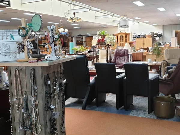 Winkelvloer van kringloopwinkel met zwarte stoelen, diverse meubels en huishoudartikelen